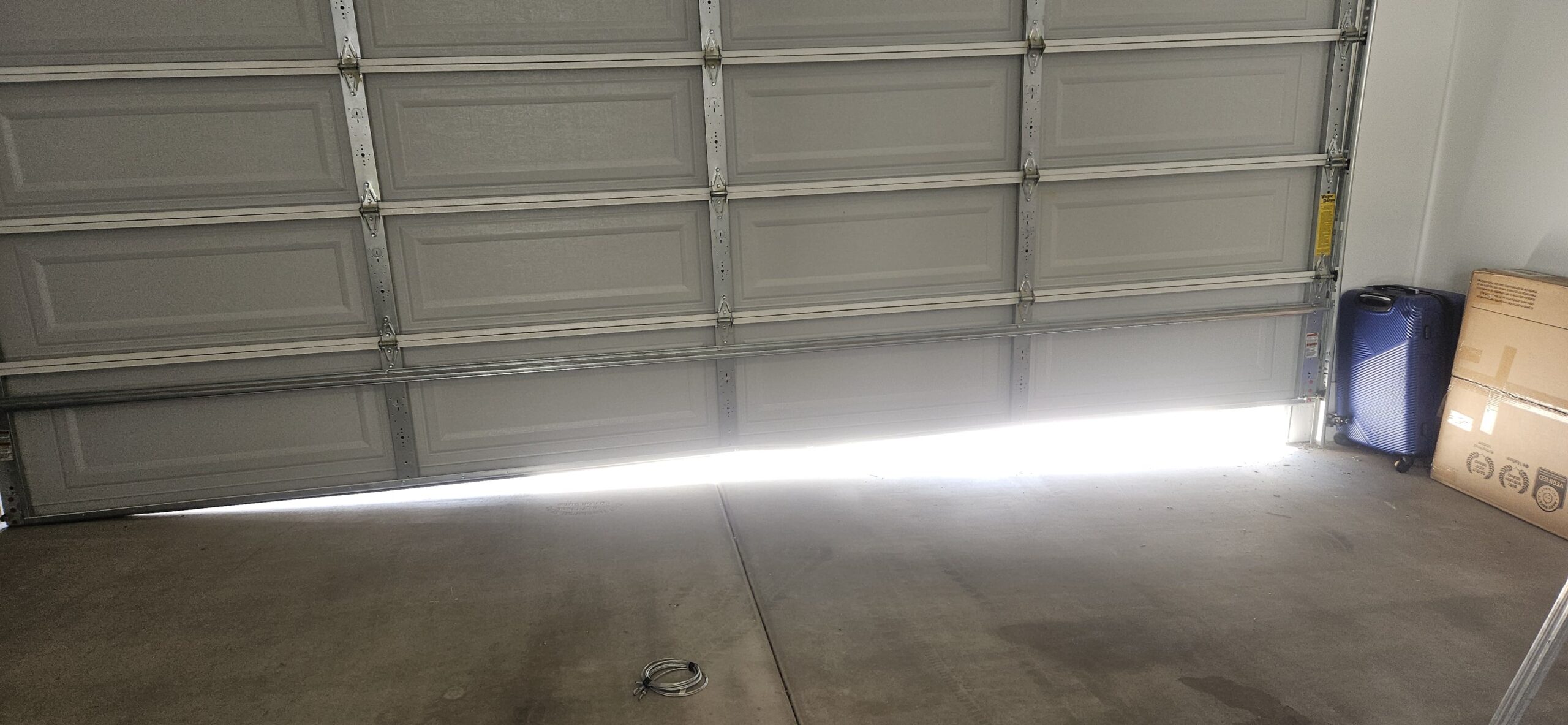 Uneven garage door with daylight visible beneath the bottom before repair in Waddell